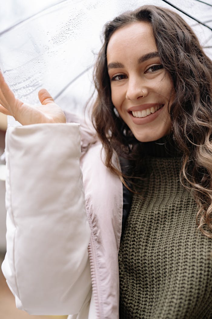 Portrait of a happy woman with umbrella enjoying a rainy day, showcasing her joyful expression.